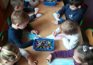 Dzieci z grupy 9 kolorują sylwetę kredki.