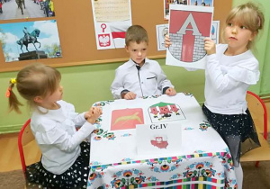 Dzieci z grupy 4 wybierają herb Aleksandrowa Łódzkiego spośród wielu innych herbów.
