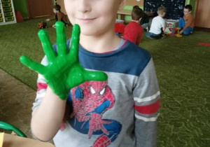 Chłopiec z grupy 2 z pomalowaną na zielono dłonią.