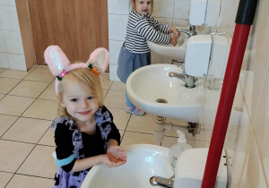 Dzieci stoją przy umywalkach, uczą się prawidłowo myć ręce.